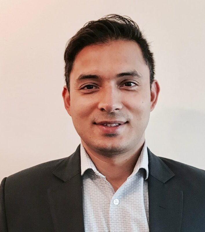 Man in a suit, smiling at camera.