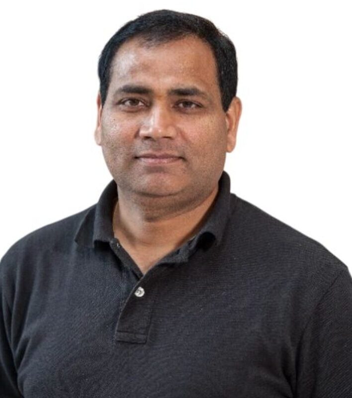 Man in black polo shirt, neutral expression.