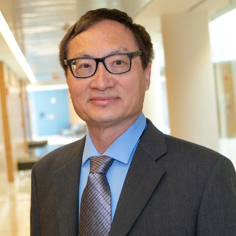Man in suit with glasses smiling indoors.