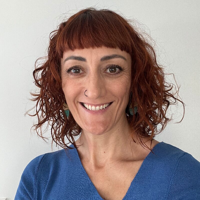 Smiling person with curly red hair.