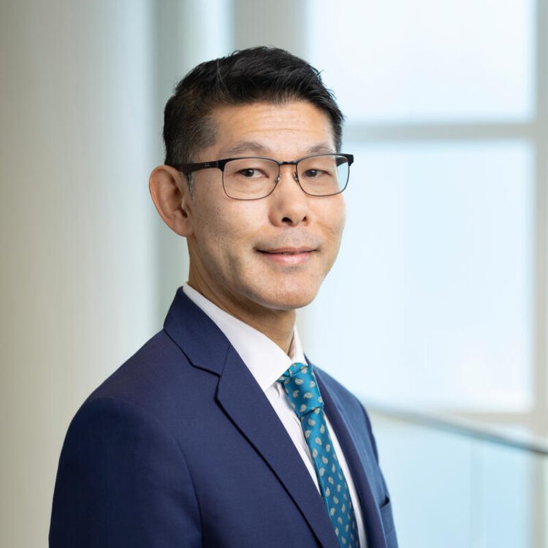 Man in blue suit with glasses smiling.